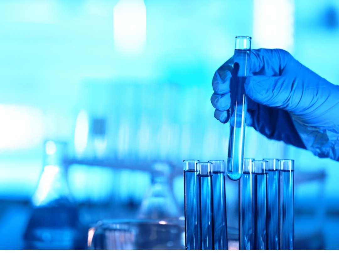 A gloved hand holding a test tube with blue liquid, possibly related to random drug testing programs.